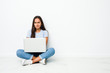 © Asier - Young mixed race indian woman sitting working on laptop frowning face in displeasure, keeps arms folded.