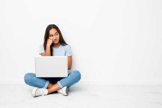 young mixed race indian woman sitting working on laptop who feels sad and pensive, looking at copy s