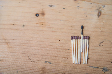 Separation concept. One burned match stands out from the rest not burned. Close up on a wooden table.