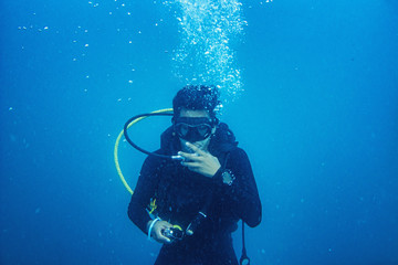 Scuba diver diving on tropical reef with blue background and reef fish at Gulf of Thailand