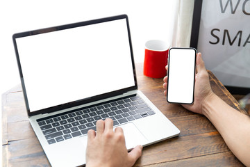 mockup image blank screen computer,cell phone with white background for advertising text,hand man using laptop texting mobile contact business search information on desk in cafe.marketing,design