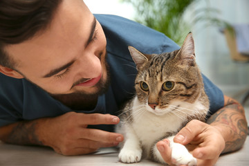 Wall Mural - Happy man with cat on floor at home. Friendly pet