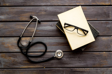 Wall Mural - Medical books near stethoscope on dark wooden background top-down
