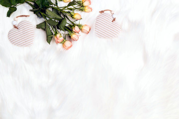 Wall Mural - A bouquet of small roses and decorative hearts on white fur background. Place for text, top down composition.