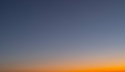 Heaven at early morning with copy space. Smooth orange blue gradient of dawn sky.Sunset, sunrise backdrop.Predawn clear sky with orange horizon and blue atmosphere.  Background of beginning of day.