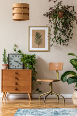 Wall Mural - Retro interior design of living room with design vintage chair and commode, plants, cacti, clock, personal accessories and gold mock up poster frame on the beige wall. Stylish home decor. Template. 