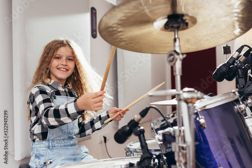 Fotografía young girl playing drums in music studio