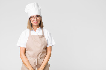 Wall Mural - middle age baker woman smiling cheerfully and casually with a positive, happy, confident and relaxed expression against flat wall