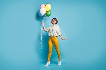 Poster - Full length photo of funny pretty lady walking surprise birthday party hold many air balloons wear casual green shirt yellow pants shoes isolated blue color background