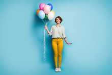Full Length Photo Of Pretty Cute Adorable Lady Surprise Birthday Party Hold Many Colorful Air Balloons Wear Casual Green Shirt Yellow Pants Shoes Isolated Blue Color Background