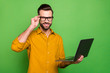 © deagreez - Profile side view portrait of his he nice attractive cheerful cheery intellectual guy in formal shirt holding in hand laptop touching specs isolated on bright vivid shine vibrant green color