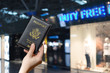 © flowertiare - Woman hand holding american passport  in the airport duty free. concept.