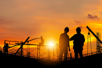 Silhouette of Engineer and worker with clipping path on building site, construction site at sunset in evening time.