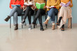 © Pixel-Shot - Young women with books sitting near color wall