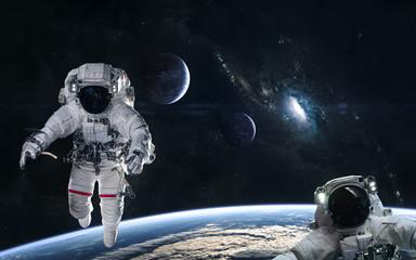 Wall Mural - Astronauts in orbit of the planet on a background of blue spiral galaxy somewhere in deep space. Science fiction. Elements of this image furnished by NASA