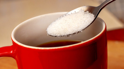 Cup of coffee and spoon with sugar closeup_