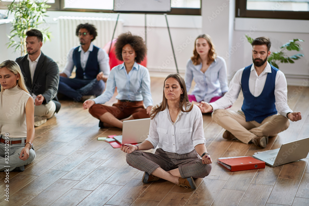 group of business coworkers meditating at work, sitting on the floor. modern, business, meditation concept - obrazy, fototapety, plakaty 