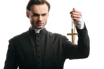 Canvas Print - serious catholic priest holding golden cross while looking at camera isolated on white