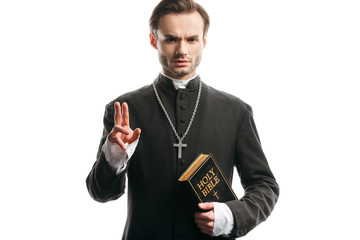 Canvas Print - confident, strict catholic priest holding holy bible and showing blessing gesture isolated on white