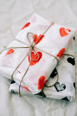 Wall Mural - two gifts wrapped in homemade wrapping paper with red and black hearts tied with jute thread for Valentine's day on a white table