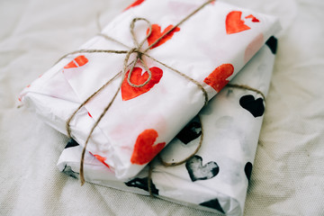 Wall Mural - two gifts wrapped in homemade wrapping paper with red and black hearts tied with jute thread for Valentine's day on a white table