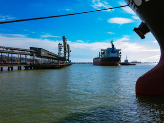 The ship is moored to the pier in the seaport on a sunny cloudy day.