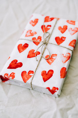 Wall Mural - a gift wrapped in homemade wrapping paper with red hearts tied with jute thread for Valentine's day on a white table