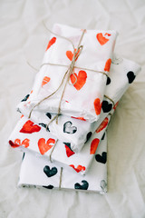 Wall Mural - a stack of gifts wrapped in homemade wrapping paper with red and black hearts tied with jute thread for Valentine's day on a white table