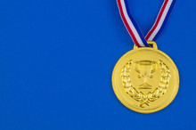 Gold Medal With Ribbon On Blue Background With Copy Space