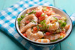 Mexican shrimp ceviche with tomato and serrano pepper on turquoise background