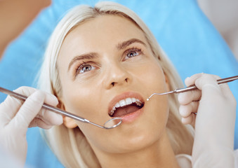 Smiling blonde woman examined by dentist at dental clinic. Healthy teeth and medicine concept