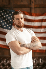 Confident American Standing Amid American Flag Hanging On The Wall