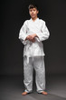 © soleg - a teenager dressed in martial arts clothing poses on a dark gray background, a sports concept
