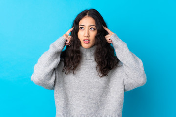 Wall Mural - Spanish Chinese woman over isolated blue background having doubts and thinking