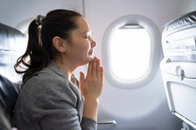 Young Woman Praying In Airplane