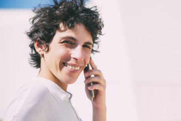 Smiling woman talking by mobile phone. Beautiful middle aged businesswoman with short hair talking by cell phone and smiling at camera outdoor. Connection concept