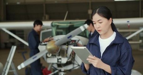 Portrait of Female engineer or pilot looking in airplane hangar to looking new aircraft drawings. Transportation and Technology concept.