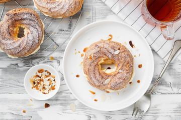 Homemade choux pastry cake Paris Brest with almond flakes and sugar powder.