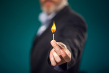 Man In Suit Holding Burning Match In Hand.