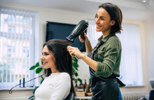 Happiness From New Hairstyle. Close-up Shot Of A Happy Smiling Professional Stylist Drying And Combing Hair Of Her Satisfied Client.