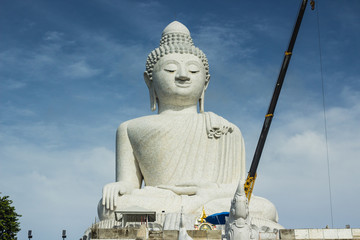 Statue of Big Buddha made of marble with a blue sky backdrop in Phuket - Thailand.