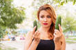 Beautiful plus size woman comparing mens penis sizes using cucumber as an example. Summer hot portrait outdoor. Copy space