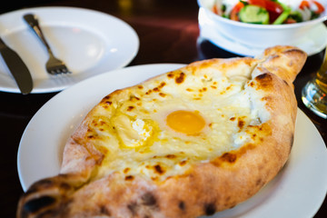 Khachapuri in Georgian restaurant - Georgian national cheese bread product, pie stuffed with cheese and eggs - Adjara Khachapuri is a famous dish from Georgia