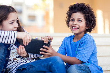 Two kids boy and girl fighting for tablet outdoor. Children and gadget addiction concept