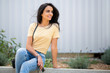 © mimagephotos - smiling beautiful young woman sitting outside with mobile phone and purse
