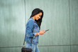 © mimagephotos - smiling young woman walking with mobile phone and purse