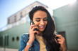 © mimagephotos - Close up smiling young North African woman talking with mobile phone outside