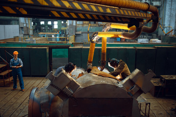 Wall Mural - Master looks at the work of two welders on factory