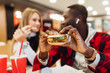 © Тарас Нагирняк - Two person are enjoying their delicious and tasty burgers in the burger-bar.