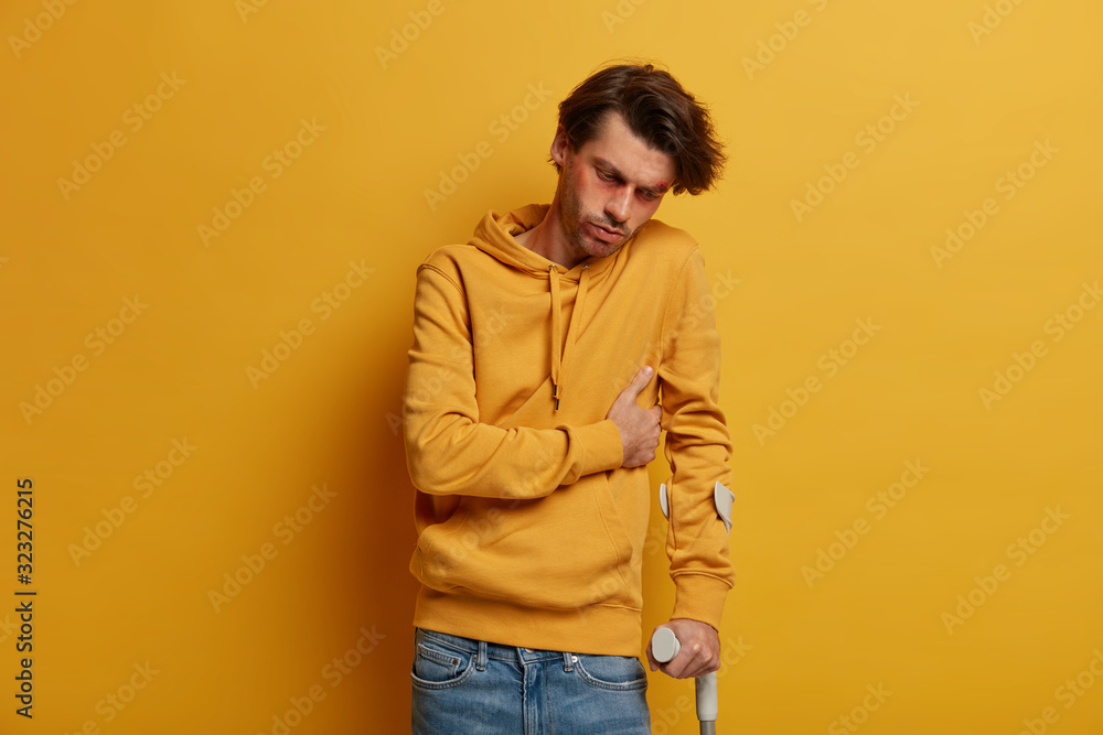 Photo Stock Depressed bruised man touches broken rib, uses crutches ...
